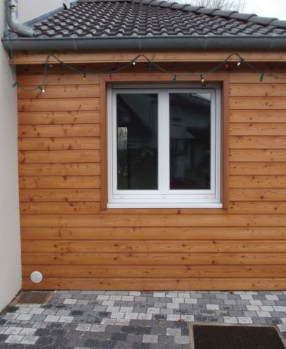 Installation de fenêtre sur mesure blanche sur façade en bardage bois à Lyon